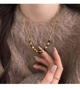 Close-up detail of brown tiger eye beaded necklace worn over a cozy fuzzy sweater