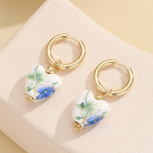 Vintage heart-shaped ceramic drop earrings with blue floral prints on golden hoops