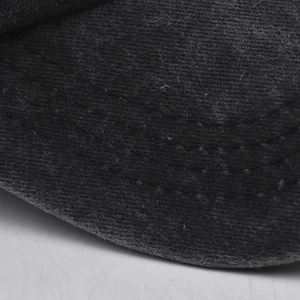 Detailed close-up of parallel stitching on the black cotton brim of a baseball cap
