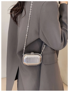 Silver mini suitcase crossbody bag with metallic mirror finish and chain strap on model