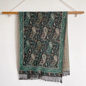 Detail view of ethnic cashmere-feel scarf with paisley patterns and decorative tassels