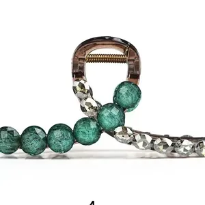 Macro shot of small hair claw with vintage green textured beads and faceted crystals