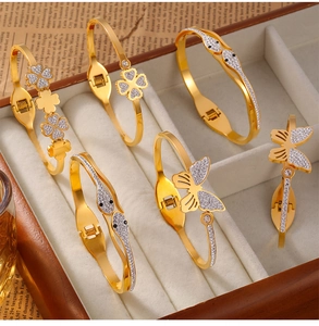 Polished gold plated titanium steel bracelets with clover and butterfly motifs in a gift box
