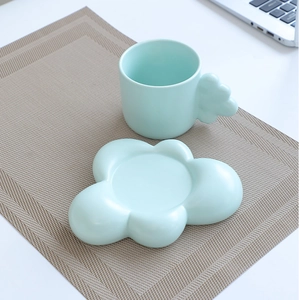Top view of mint green cloud-shaped ceramic mug and saucer set on an office desk