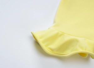 Vista macro dell'abito giallo che mostra il tessuto morbido e l'orlo con volant