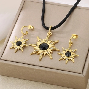 Parure bijoux soleil doré avec pierre noire et boucles d'oreilles sur boîte beige