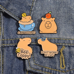 Cute capybara enamel pins set featuring bee and cappyccino designs on denim fabric