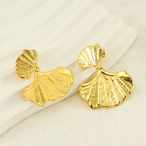 Detailed close-up of golden ginkgo leaf earrings with fine textured veins on a soft background