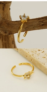 Détail de bagues ajustables dorées avec zircons cœur et étoile sur bois et céramique