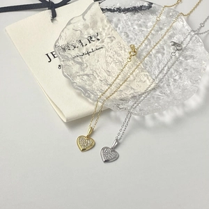 Close-up of heart-shaped pendants with pavé-set stones in gold and silver finishes
