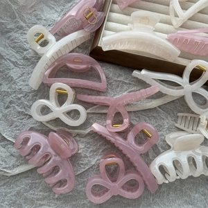 Detailed close-up of jelly-colored thick shark clips in pink and beige on fabric