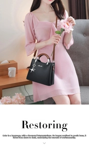 Detail of black pebbled leather handbag with brown handles and star-shaped pendant charm