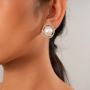 Close-up of golden earring featuring a faux pearl center and sparkling rhinestone halo