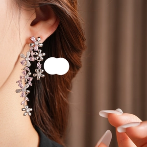 Close-up of sparkling flower earrings with pink stones on model with elegant styling