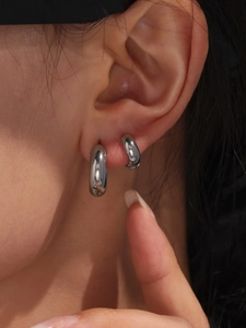 Macro shot of minimalist thick polished silver hoop earring on model with mirror finish