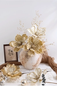 Close-up of champagne gold artificial magnolia flowers with glitter in a ceramic vase