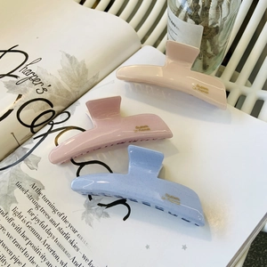 Detailed view of three glitter acetate hair claws in pink and blue on a magazine