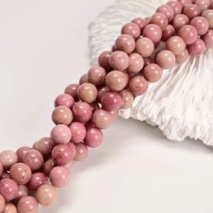 Macro detail of natural pink rhodonite beads with unique wood grain patterns for DIY jewelry