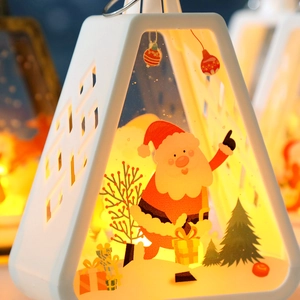 Close-up of white triangular Christmas lantern featuring Santa Claus and warm LED light