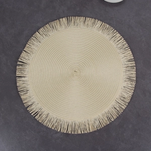 Detail of round beige woven placemat with fringed edges and spiral texture design