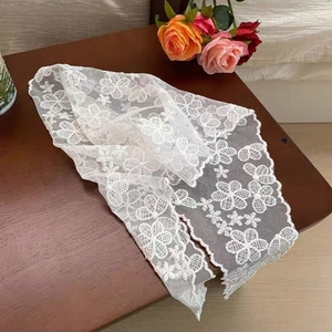 Detailed close-up of white floral lace fabric with scalloped edges on a wooden table