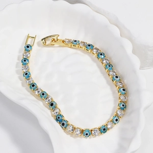 Detail of gold evil eye tennis bracelet with blue enamel and sparkling zircon stones