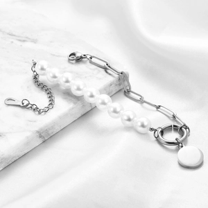 Minimalist pearl and paperclip chain bracelet with silver pendant on silk background