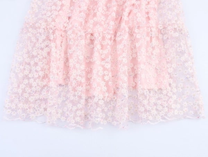 Détail de la robe en dentelle de tulle rose pâle à fleurs avec des textures délicates