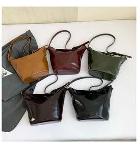 Macro shot of multiple vintage glossy bucket bags in brown, green, and burgundy