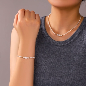 Elegant pearl necklace and bracelet set with golden beads shown on a female model