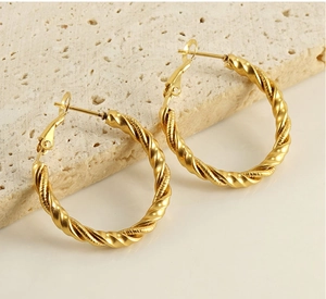 Macro detail of gold-plated stainless steel hoop earrings with spiral twisted texture