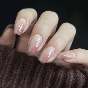 Detailed close-up of glossy short square press-on nails with nude blush gradient effect