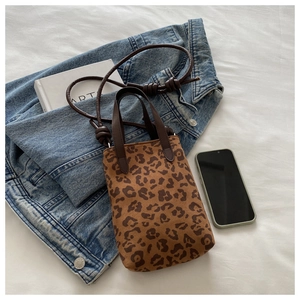 Leopard print mini tote bag styled on blue denim jacket with lifestyle accessories