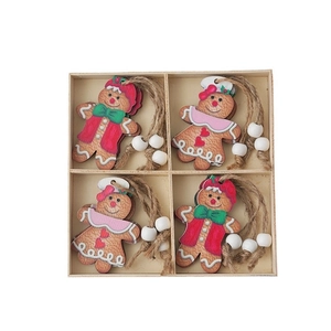 Wooden gingerbread man Christmas tree ornaments set with twine and beads in a wooden tray