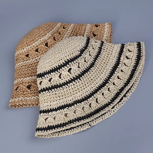 Detailed view of hand-crocheted paper straw hats featuring wavy stripe cut-out patterns