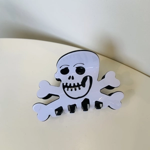 Detailed view of skull and crossbones hair claw clip for Halloween festive styling