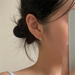 Close-up of minimalist pink cat eye stone and 925 silver stud earring on model's ear