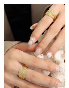 Close-up of a multi-layer gold textured ring worn on model with elegant nail art