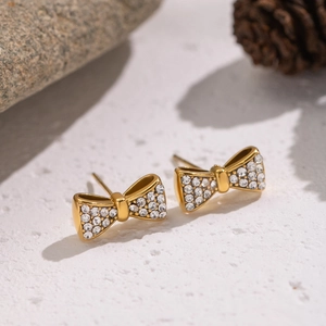 Boucles d'oreilles nœud dorées avec strass brillants sur pierres naturelles et pommes de pin