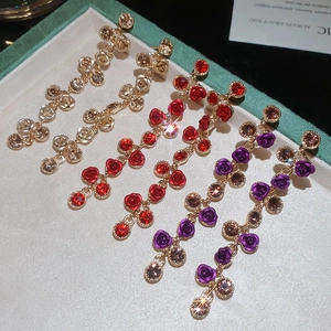 Macro detail of elegant rose pendant tassel earrings with sparkling rhinestones in a velvet box