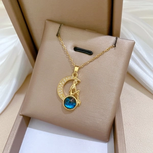 Detail of gold moon and figure pendant with blue gemstone on silk background
