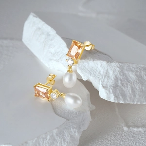 Close-up of S925 silver gold-plated earrings with orange zircon and white pearl drops