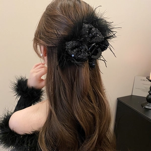 Close-up of elegant black hair claw clip with sequins and fluffy feather details