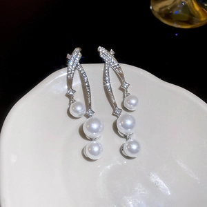 Vue macro de boucles d'oreilles argentées avec cristaux et trois perles blanches