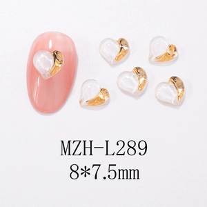 Macro detail of transparent heart-shaped nail charms with gold trim for DIY manicure art