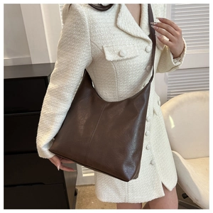 Brown PU leather tote bag shown on a model's shoulder in a lifestyle indoor setting