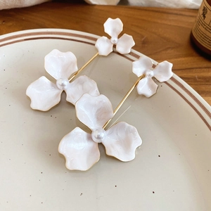 Detail of elegant white floral drop earrings with pearls on a ceramic plate