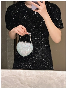 Detailed view of heart-shaped evening bag with sparkling rhinestones and silver handle