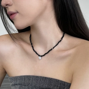 Close-up of S925 silver heart clover necklace with black beads on model neckline