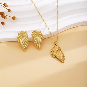 Close-up of golden wing necklace and earrings set on an elegant minimalist background